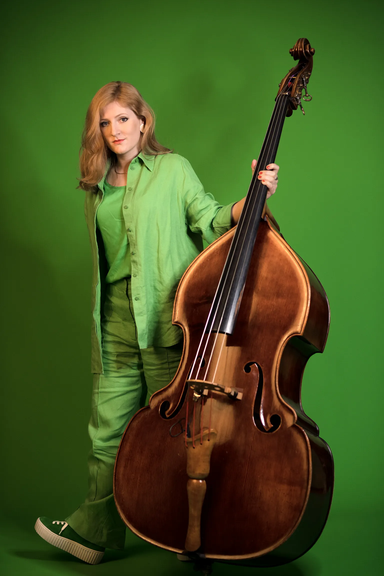 Lisa Wulff vor grünem Hintergrund mit ihrem Kontrabass
