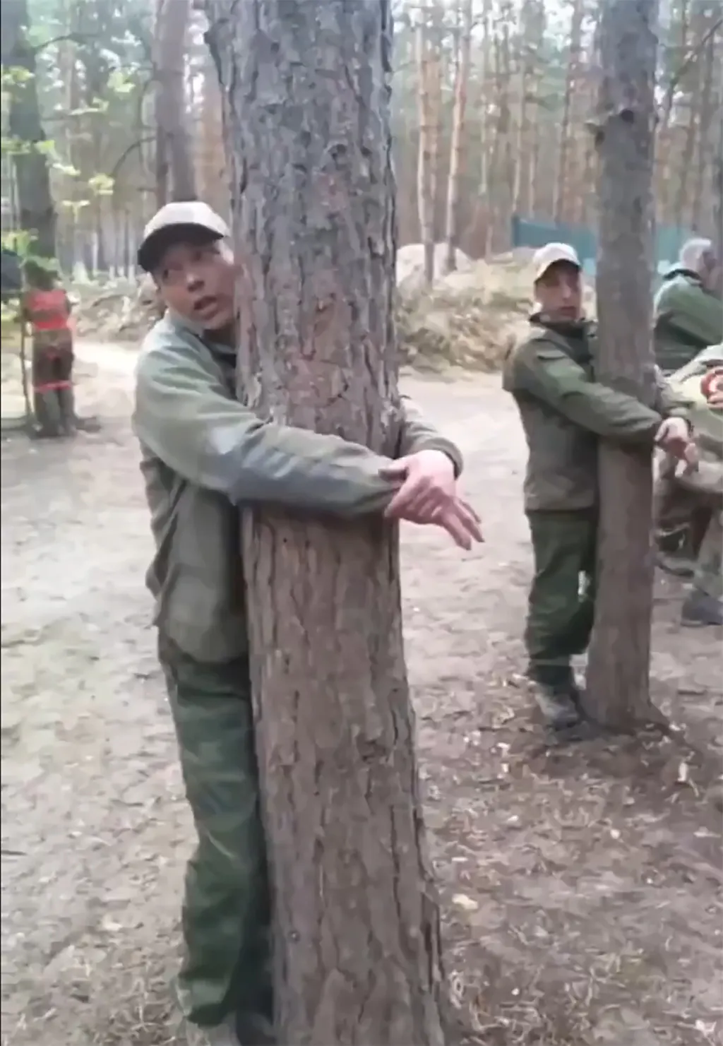Mehrere russische Soldaten werden von Russen an Bäume gebunden.
