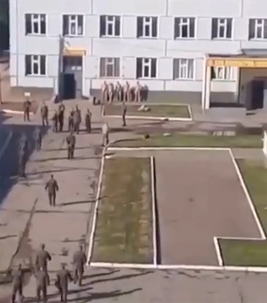 Screenshot: Russische Soldaten werden in einer Kaserne gezwungen, nackt mit den Händen das Gras zu schneiden.