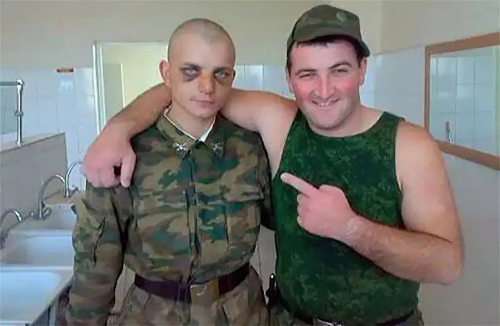 Ein älterer Soldat posiert lächelnd Arm in Arm mit einem jüngeren mit zwei blauen Augen.