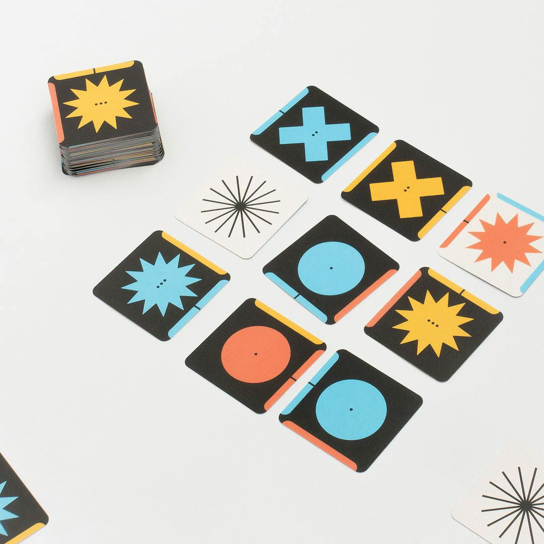 Stack and spread of square cards with geometric shapes in blue, red, and yellow on a white surface