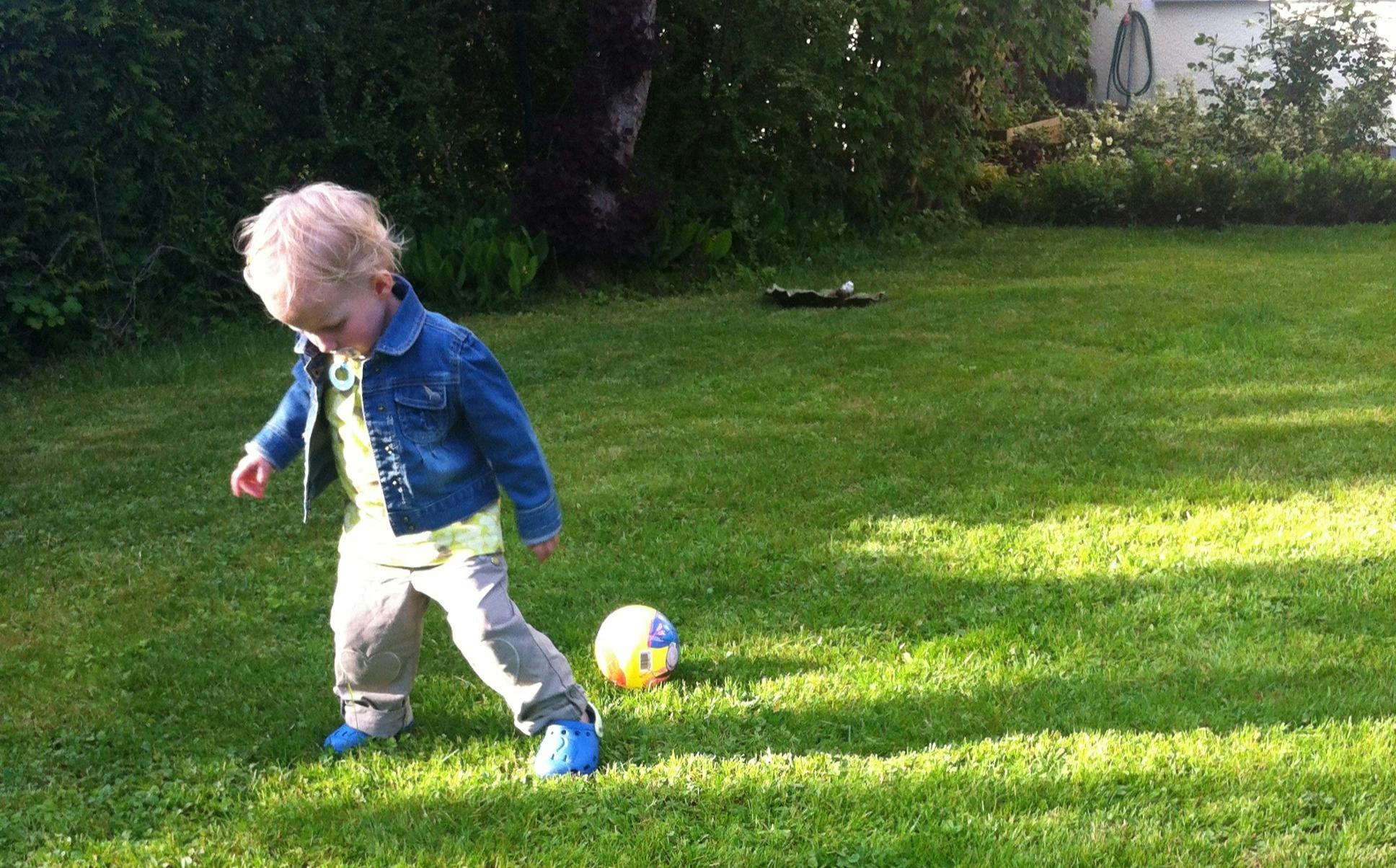Kind mit Schnuller spielt Ball