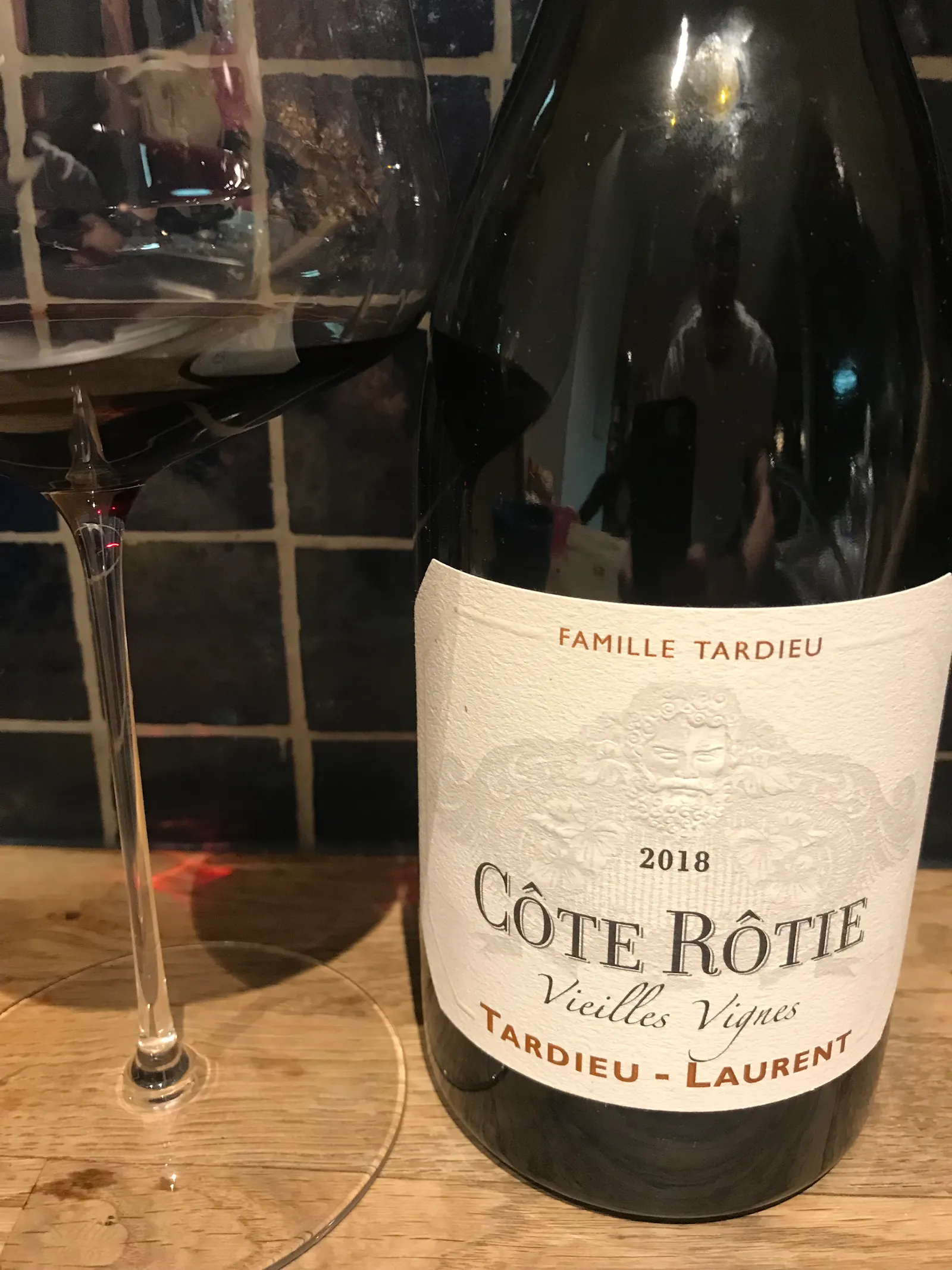 Rotweinflasche und ein Weinglas mit Rotwein stehen auf einer Ablage