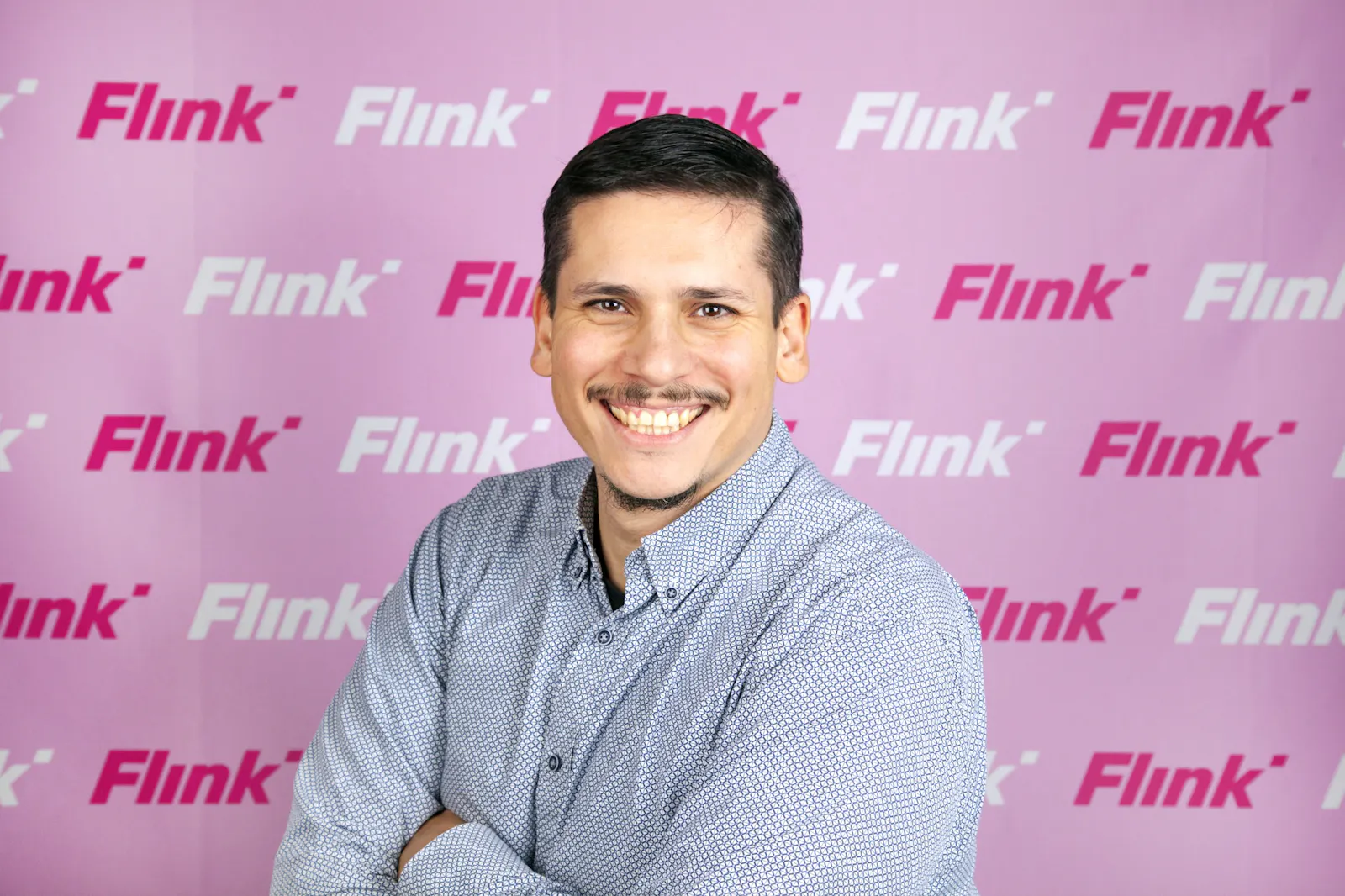 Onel Morales y Fernandez lacht vor einem Hintergrund, auf dem Flink steht