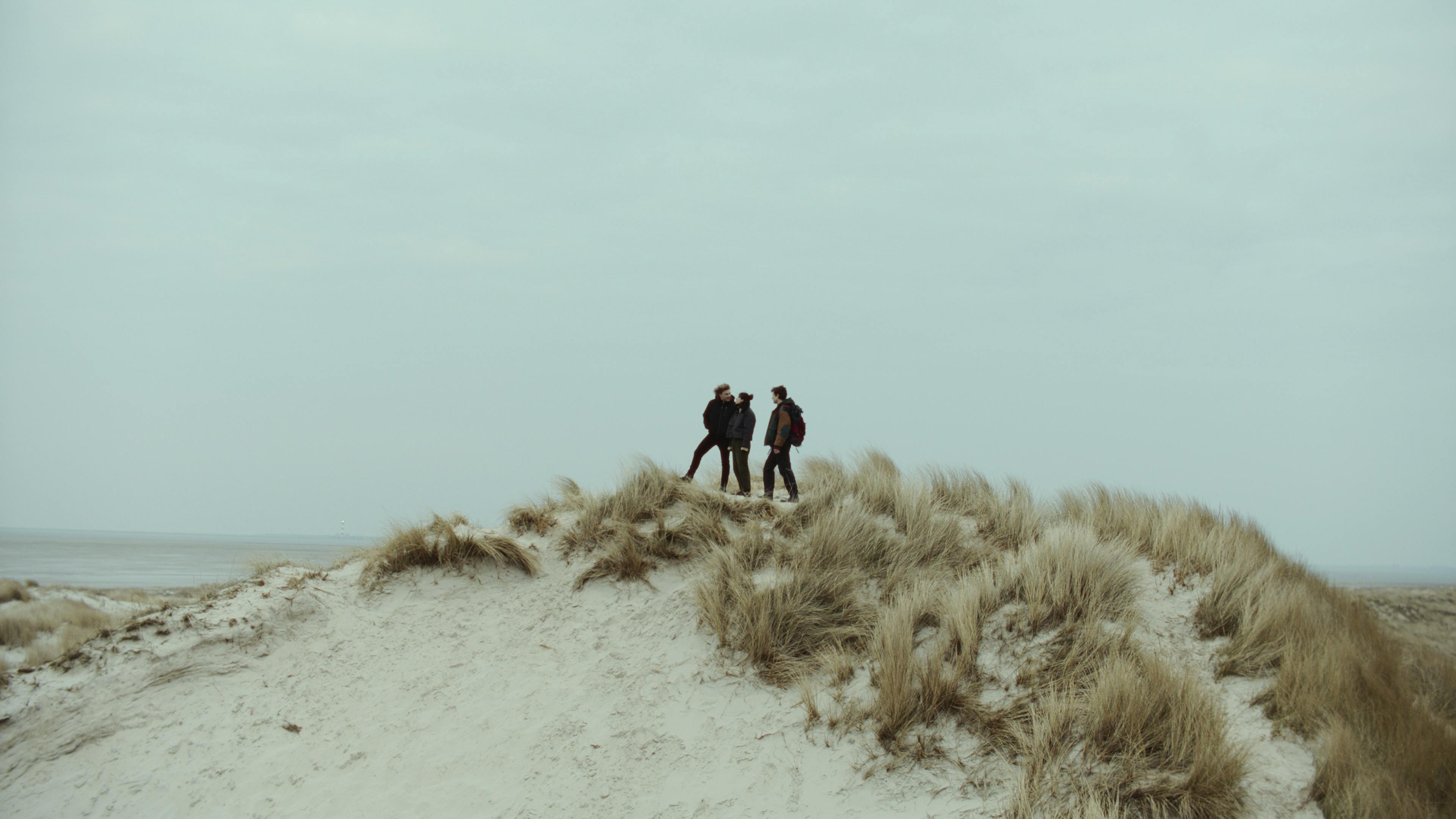 Das Dreiergespann auf der Düne - Fiete (Leonard Scheicher, r), Luca (Johannes Nussbaum, l) und Amiri (Zeynep Bozbay, m) // © Schmidbauer-Film, Nikolai Huber