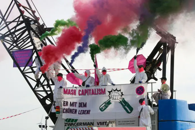 Protest von Ende Gelände, Besetzung eines Baggers, Transparent: smash capitalism, her mit dem schönen Leben
Menschen ins weißen Maleranzügen, bunter Rauch