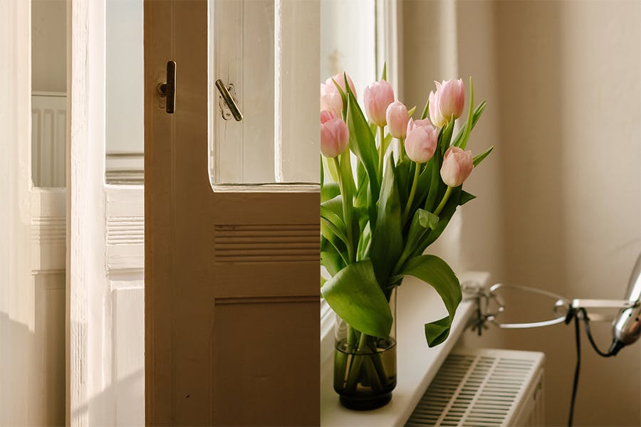 Geöffnete Balkontür. Frische rosa Tulpen in einer Glasvase auf einem alten Fensterbrett.