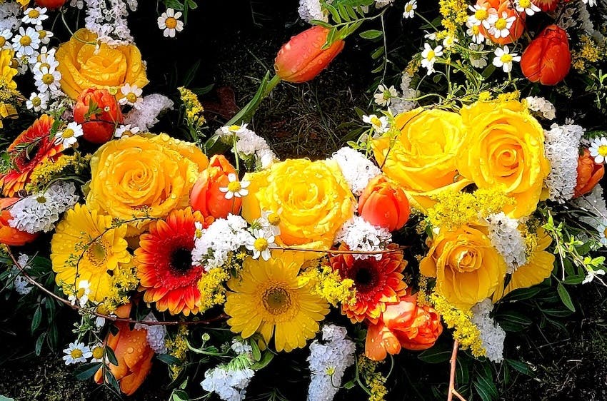 Gelbe, weiße und orange Blüten in einem Kranz mit Tulpen, Gerbera und Rosen