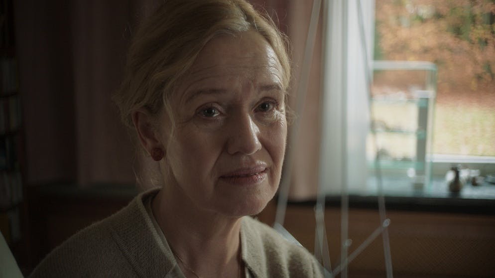 Erika Schönfeld (Marion Reuter) sitzt auf der Sofakante und wird von Kommissar Felix Voss befragt // Bild: BR/Hager Moss Film GmbH/Hager/Daniela Knapp