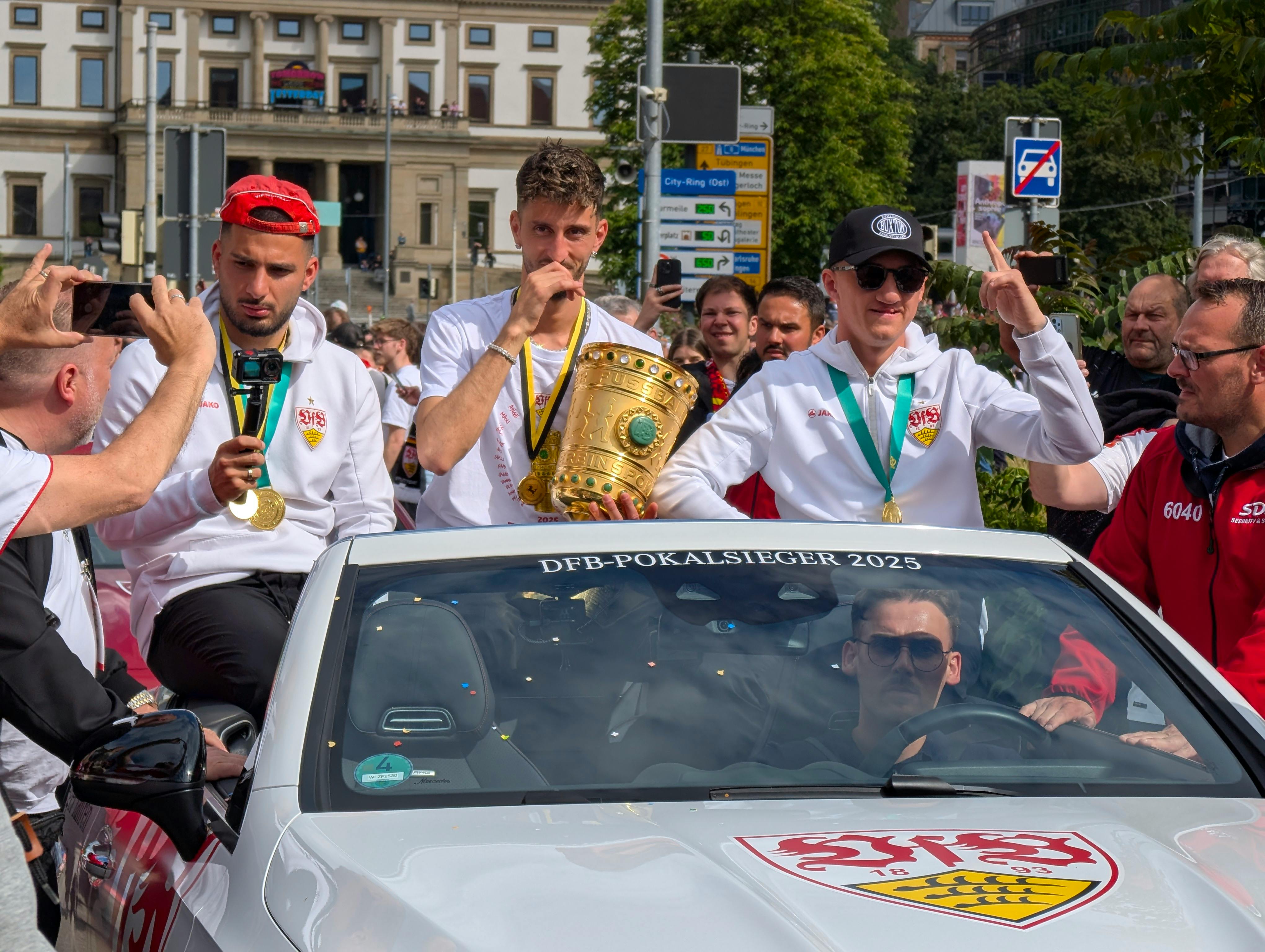 VfB-Kapitän Atakan Karazor mit dem DFB-Pokal, links Deniz Undav, rechts Angelo Stiller. Foto: Jürgen Brand