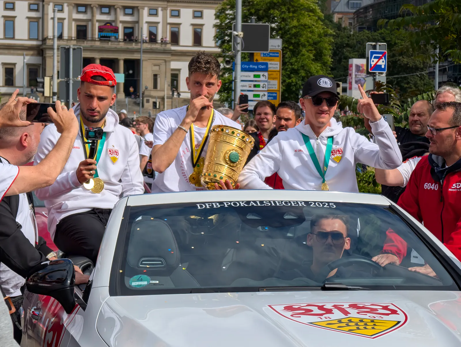 VfB-Kapitän Atakan Karazor mit dem DFB-Pokal, links Deniz Undav, rechts Angelo Stiller. Foto: Jürgen Brand