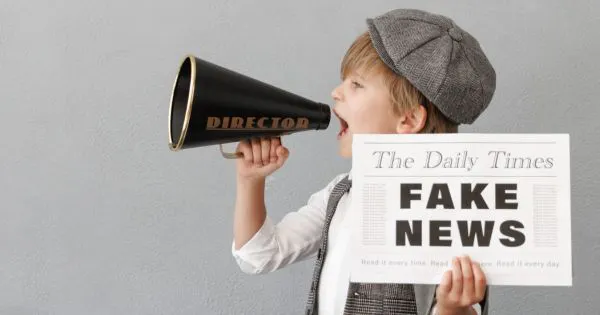 Ein Junge mit einem Megaphon in der Hand und einer Zeitung, die mit "FAKE NEWS" betitelt ist / Bild: Canva