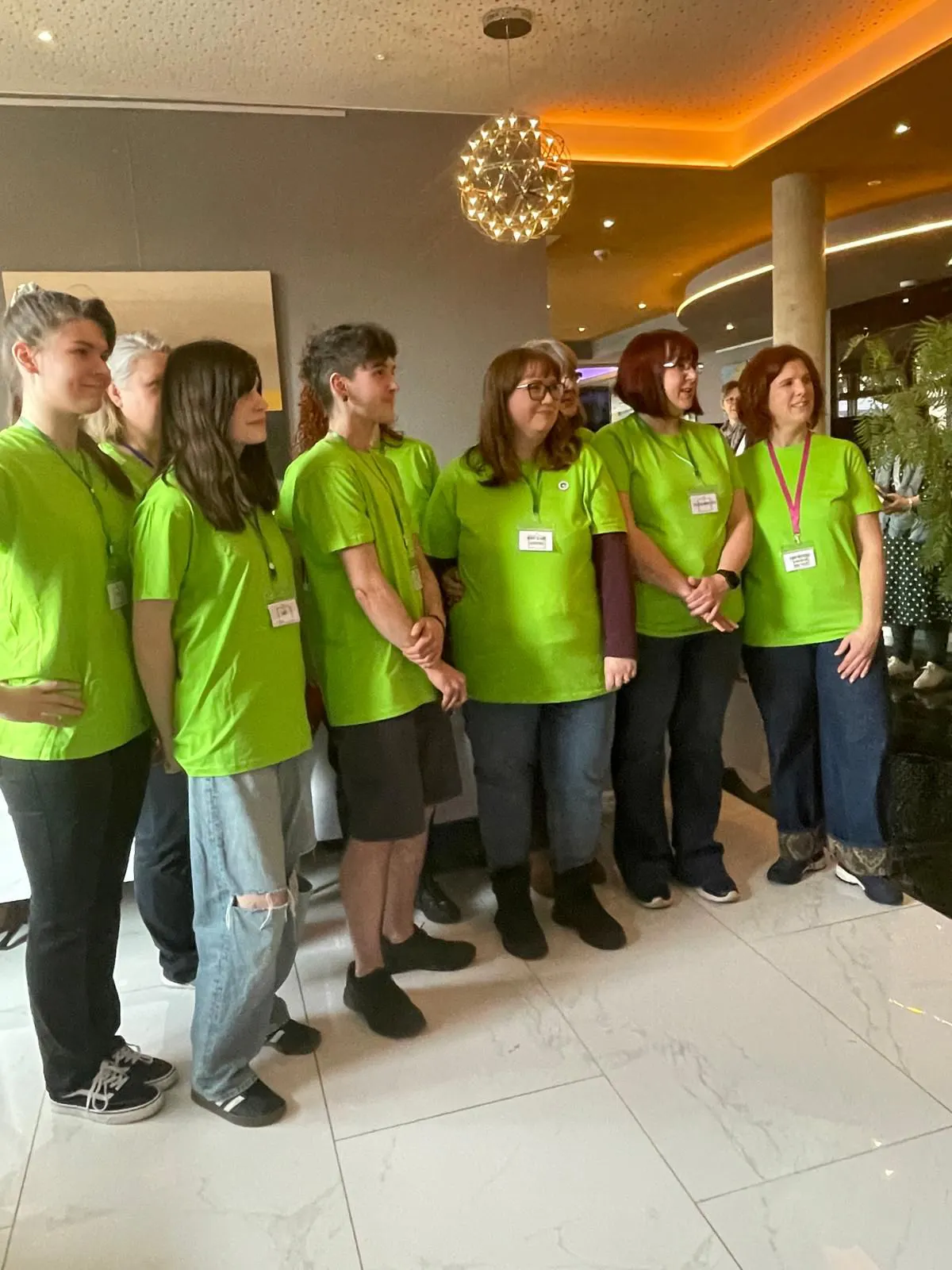 sieben stehende Personen in grünen T-Shirts