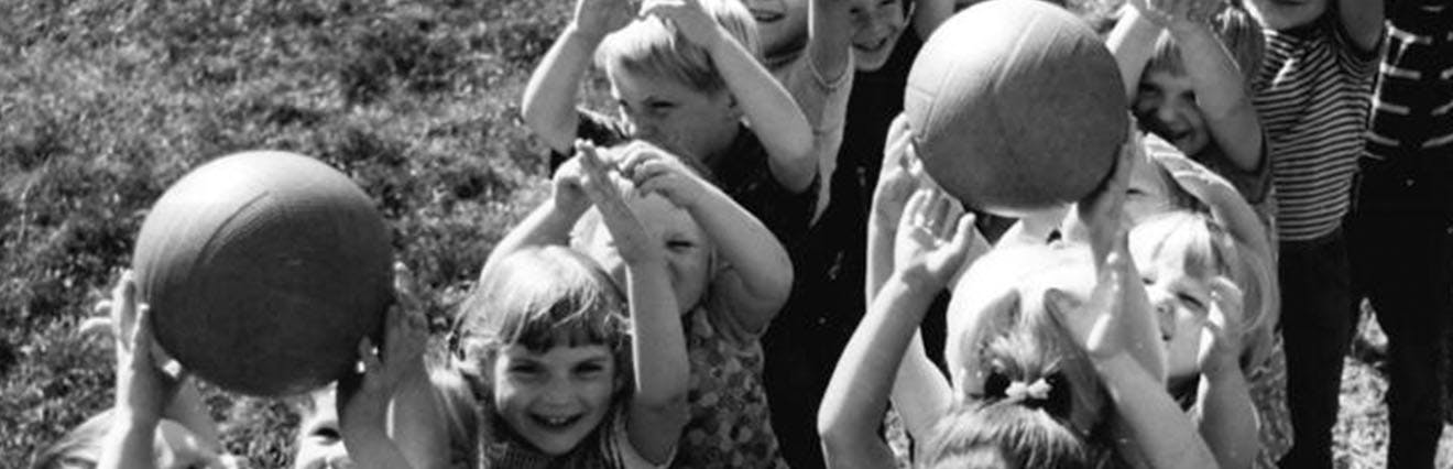 Schwarz-weiß-Bild zeigt Kinder, die mit Bällen spielen