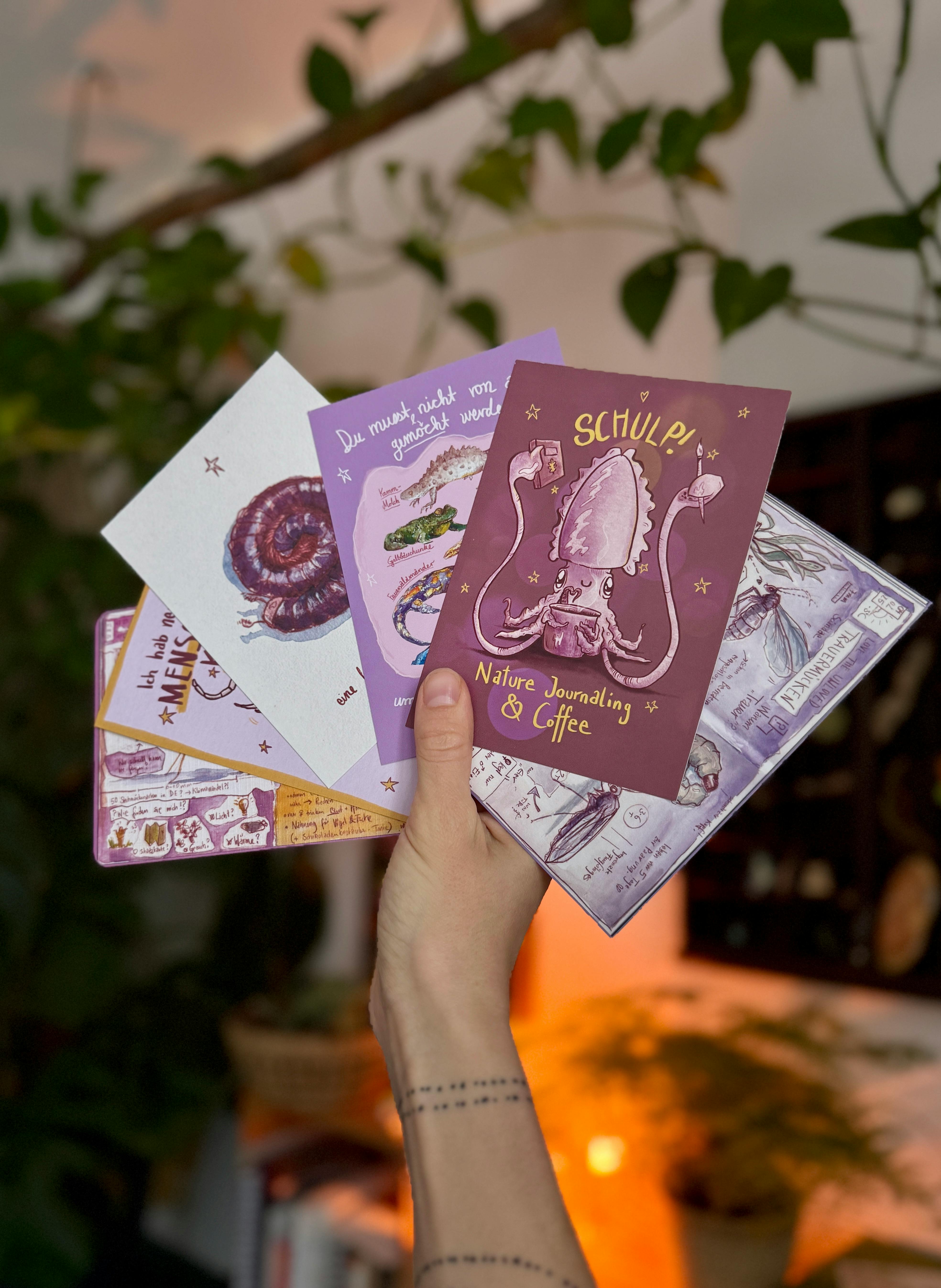 Ein paar Beispiele vergangener Postkarten der Nature Journaling Wieder Wilder Werden Schneckenpost. Eine Hand hält von unten ins Bild sechs Postkarten. Auf der vordersten ist ein Tintenfisch zu sehen, der aus einer großen Kaffeetasse trinkt. Da drüber steht schuld, unten drunter Natur Journal Coffee. Die andere Motive sind nicht genau zu erkennen. Alle sind Naturmotive.