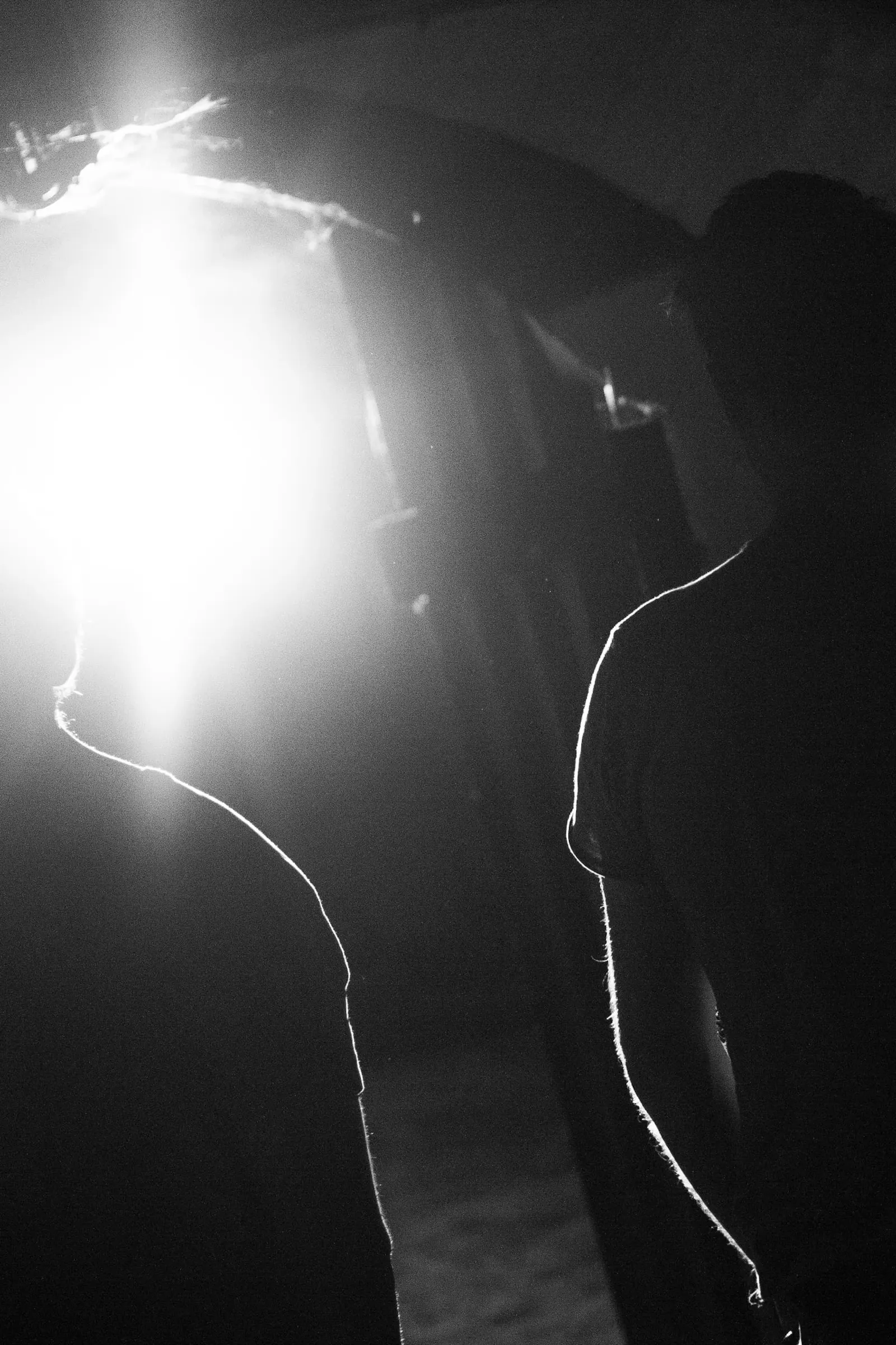 Two men stand silhouetted by a light