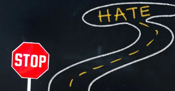 Eine Stop-Tafel vor einer Straße, die zu Hate / Hass führt / Bild: Canva