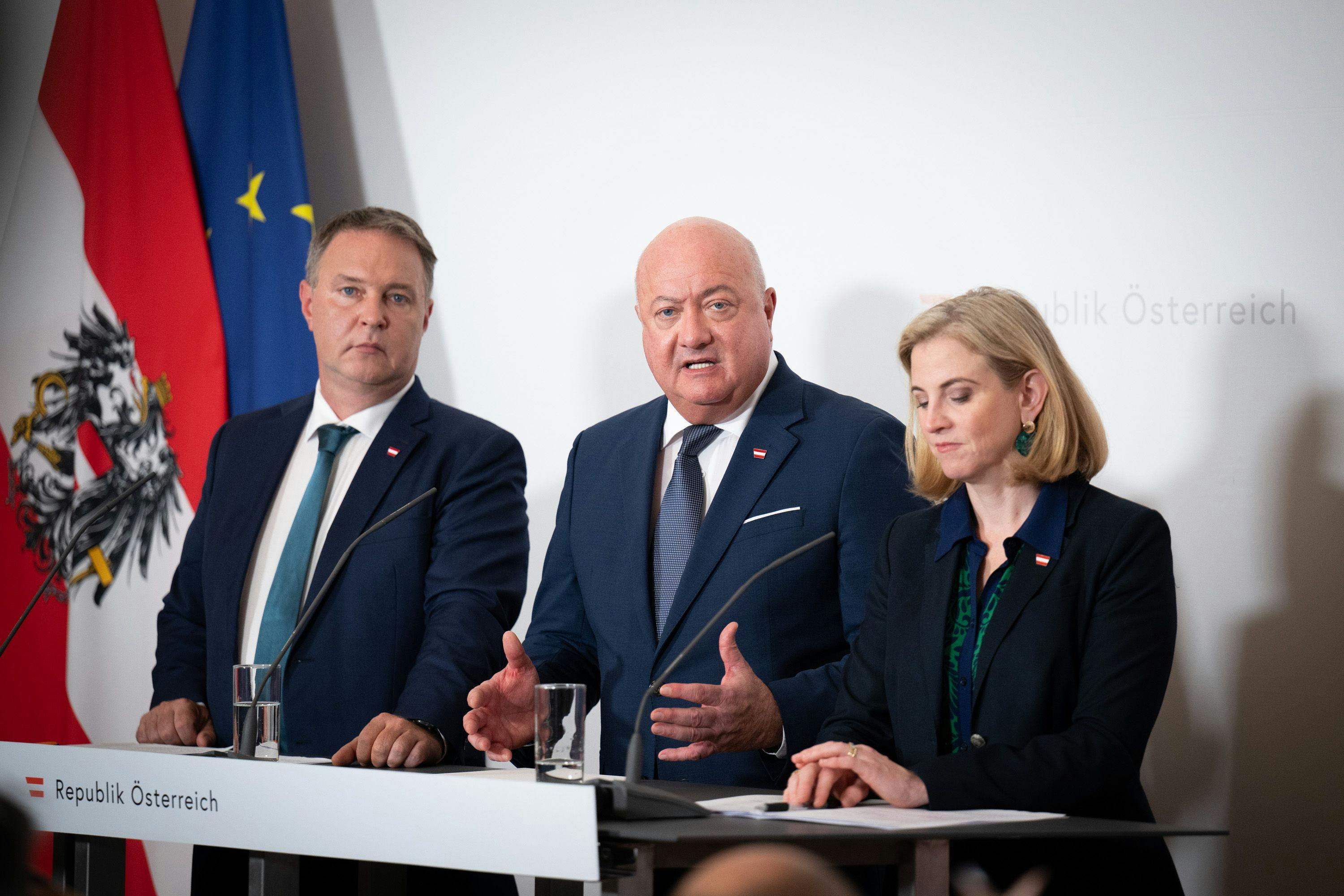 Auf dem Bild sieht man Bundeskanzler Christian Stocker (Mitte), Vizekanzler Andreas Babler (links) und Bundesministerin Beate Meinl-Reisinger (rechts) bei einer Pressekonferenz.