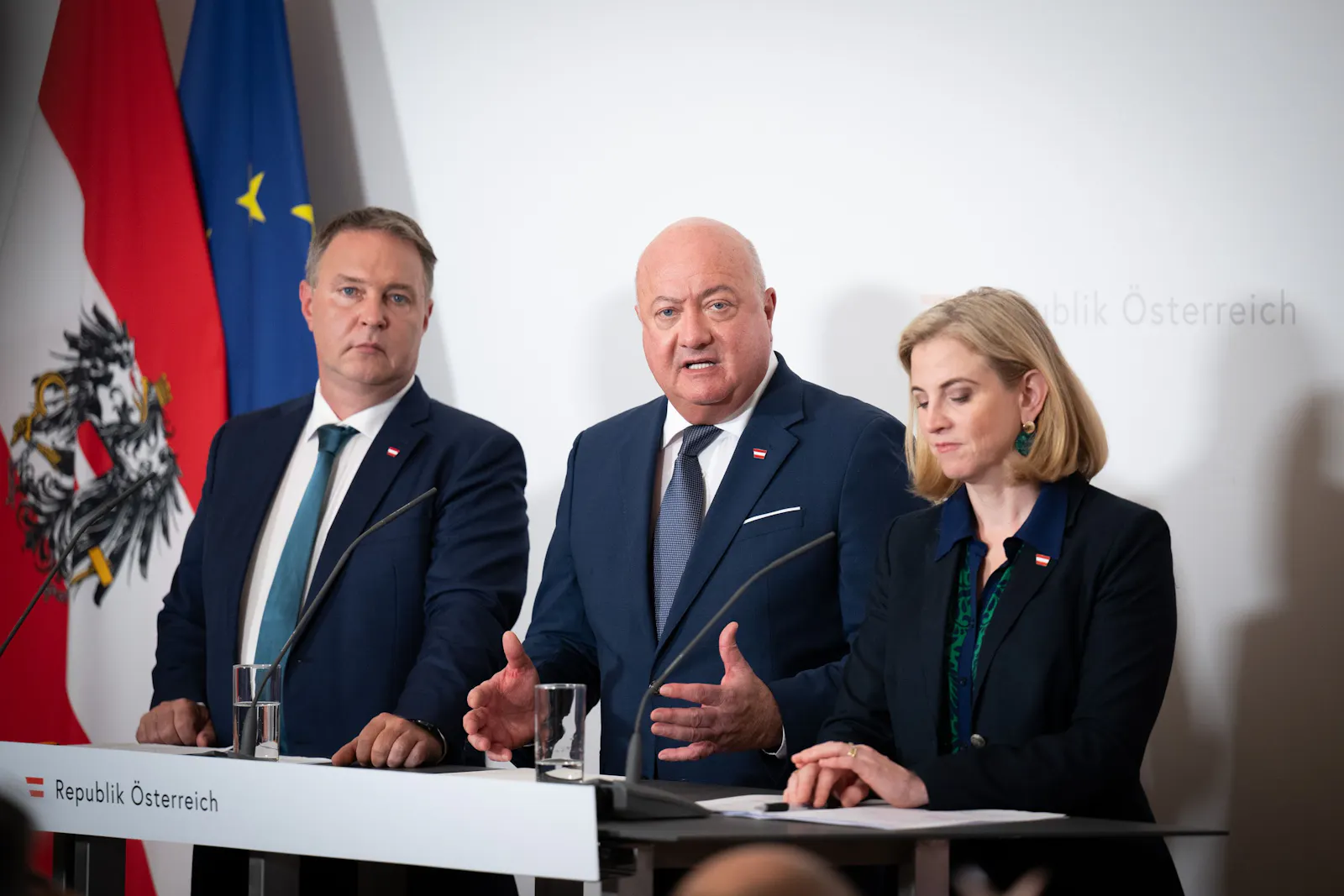 Auf dem Bild sieht man Bundeskanzler Christian Stocker (Mitte), Vizekanzler Andreas Babler (links) und Bundesministerin Beate Meinl-Reisinger (rechts) bei einer Pressekonferenz.