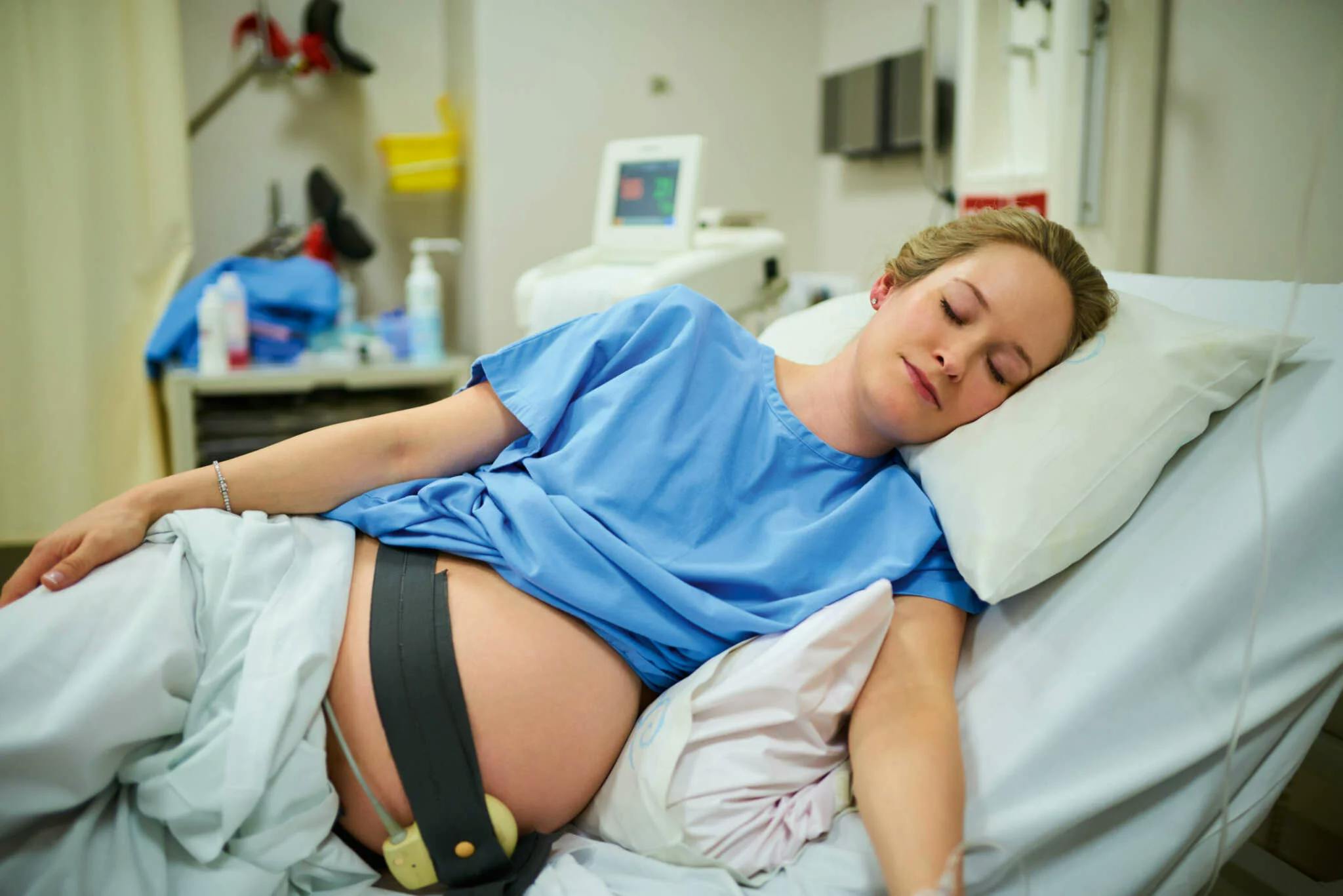 Eine schwangere Frau liegt auf einem Klinikbett, um ihren Bauch ist ein Wehenschreiber gelegt