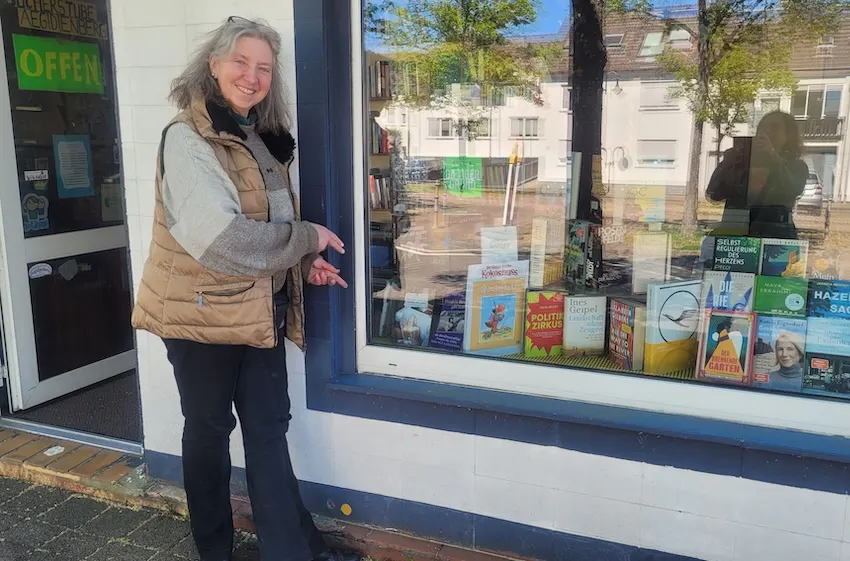 Buchhändlerin Verena Groß vor dem Schaufenster ihrer Bücherstube in Aegidienberg, in dem das Buch "17 JAHRE DEMENZ – So long, liebe Mama" von Christine Piontek ausliegt