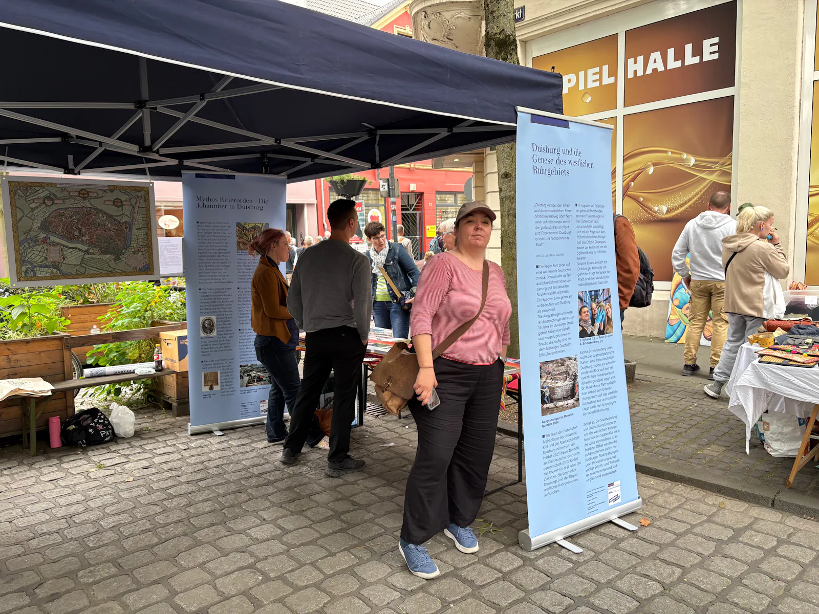 Ein Mensch steht vor einem Pavillion mit Info-Rollups.