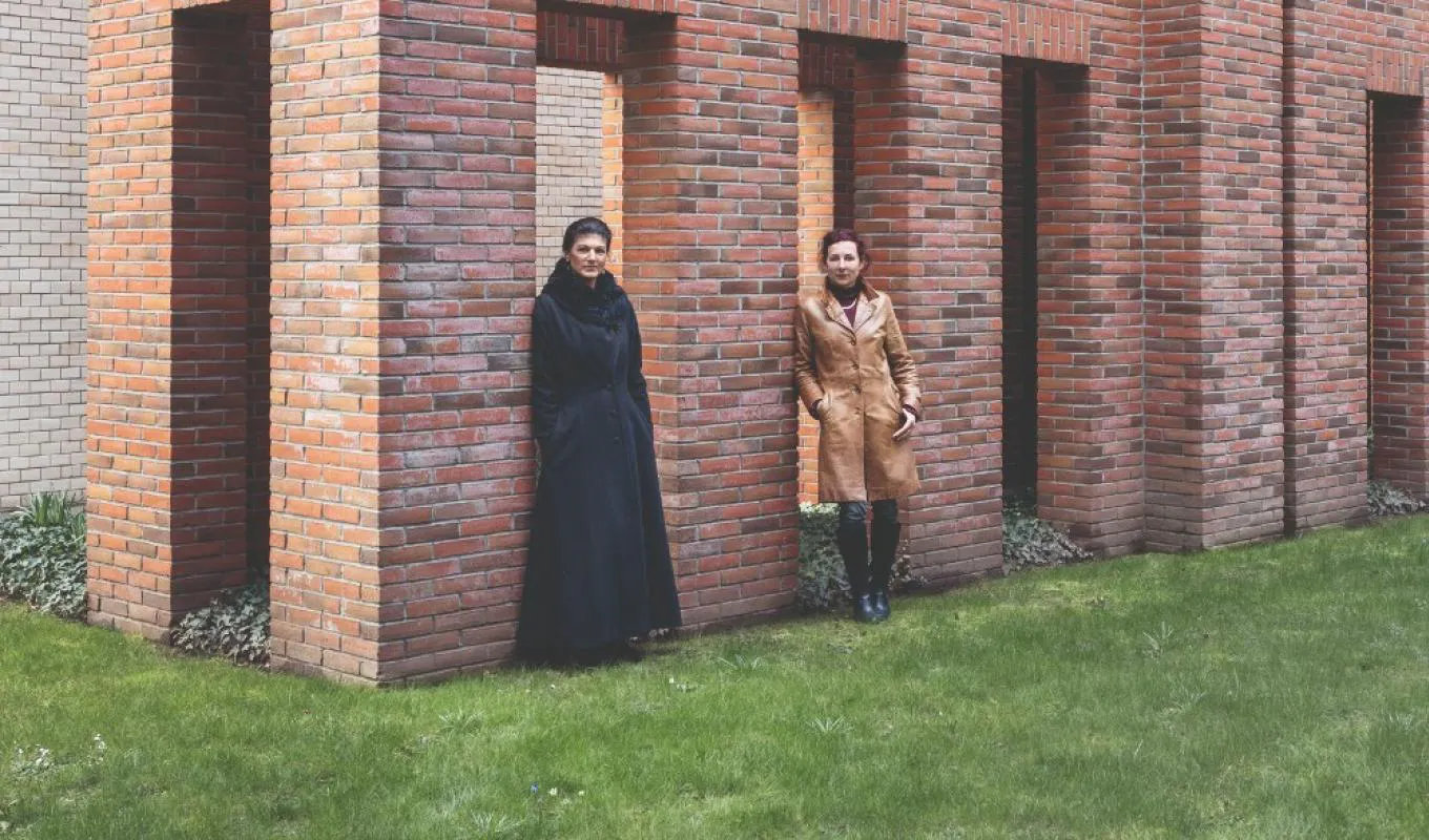 Sahra Wagenknecht und Juli Zeh stehen vor einer Backsteinfassade und posieren für entweder ein Interview oder ein Metalbandcover