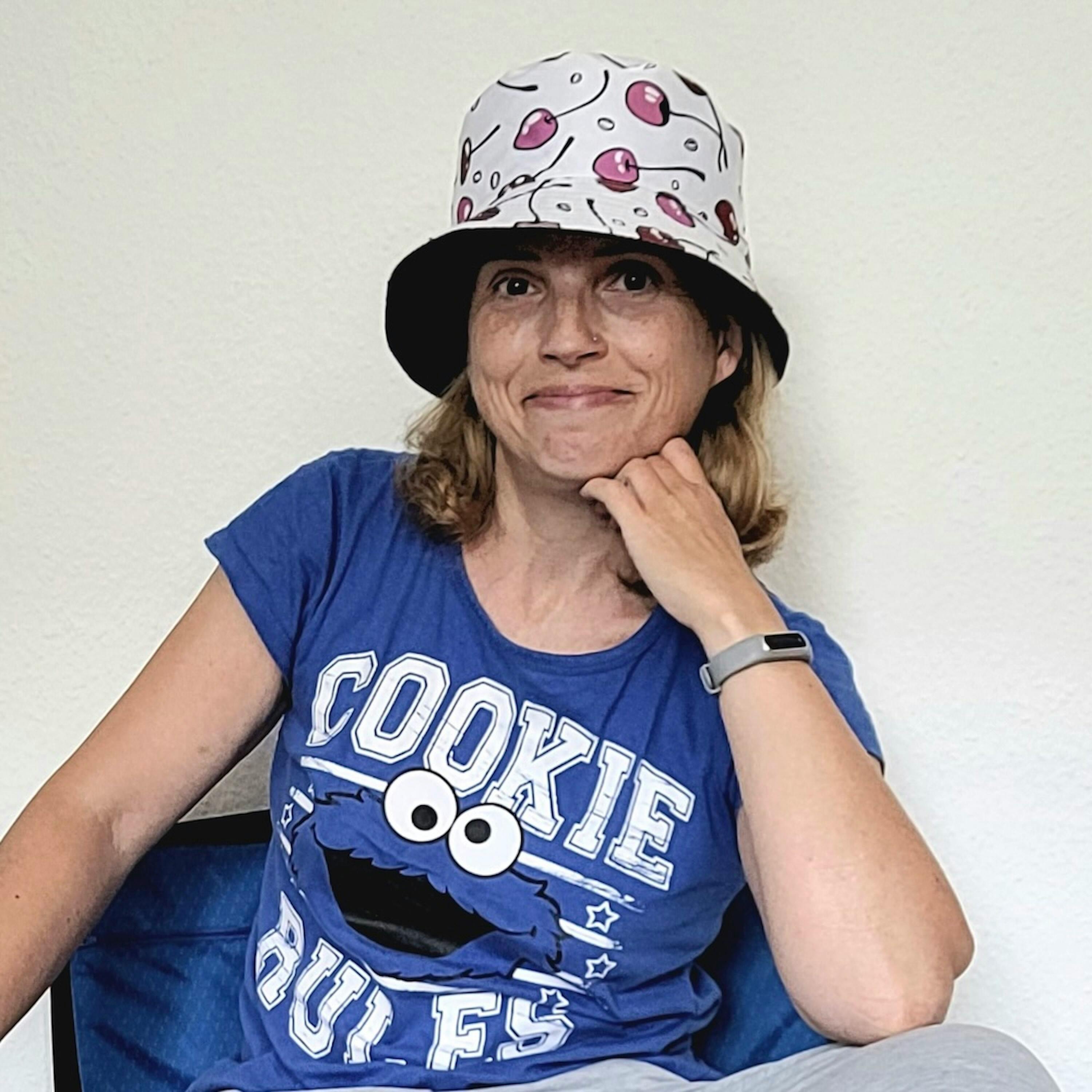 Christine Piontek mt einem weißen Sonnenhut mit rosa Kirschen sitzt in einem Koffer