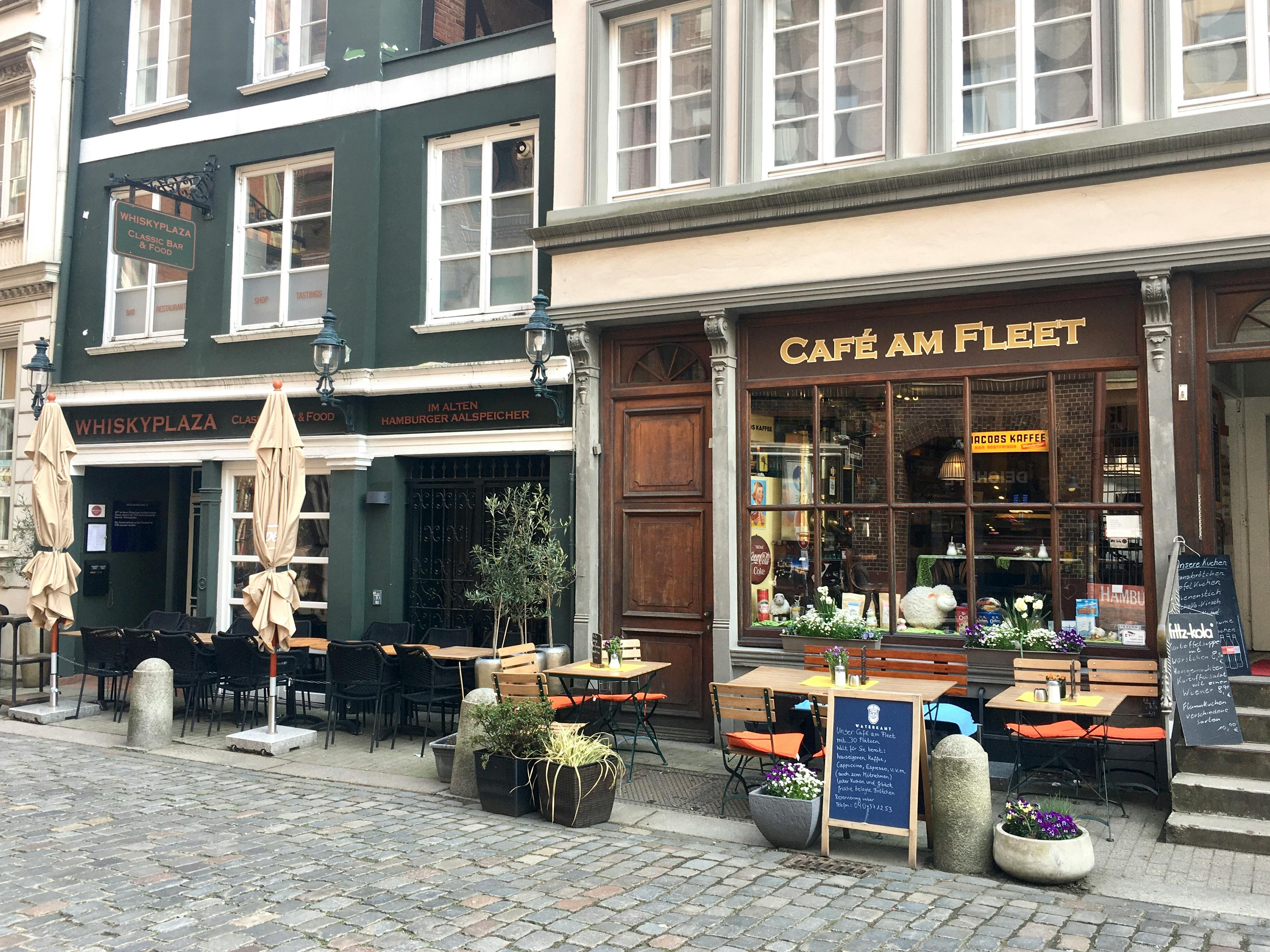 Zwei Lokale Whiskyplaza und Café am Fleet mit Tischen, Stühlen, Schirmen und Schildern