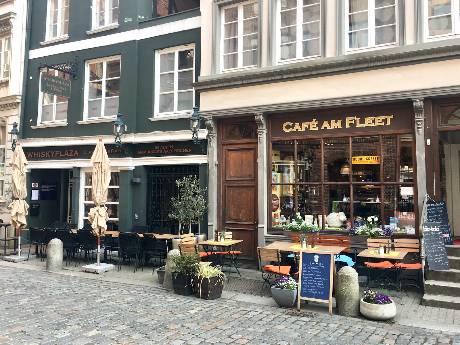 Zwei Lokale Whiskyplaza und Café am Fleet mit Tischen, Stühlen, Schirmen und Schildern