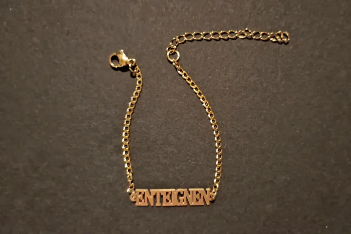 Ein goldfarbenes Armband mit dem Schriftzug ENTEIGNEN.
