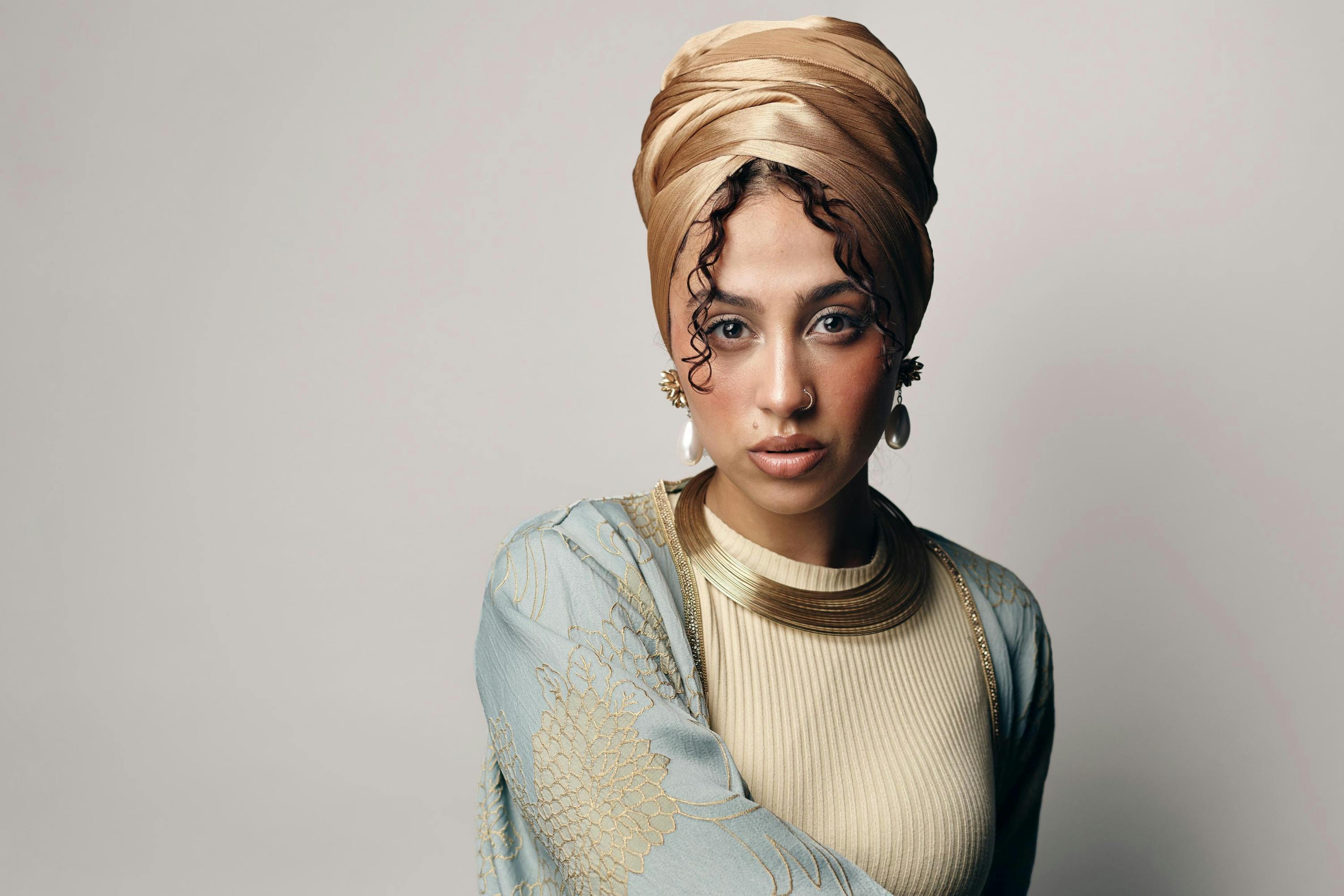 Tua El-Fawwal trägt einen goldfarbenen Hijab, ein beiges Oberteil und eine hellblau-goldene Robe und Goldschmuck