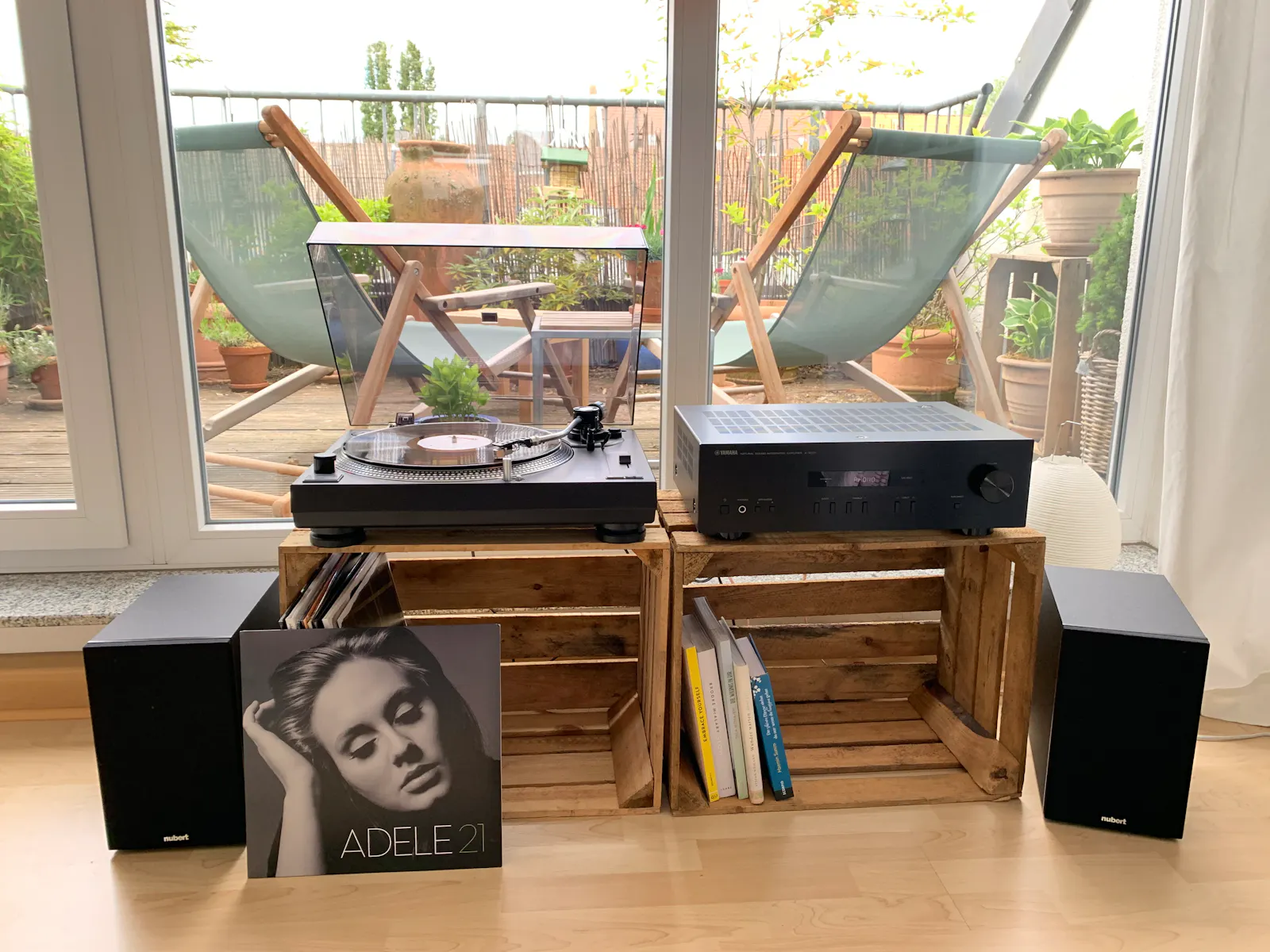 Zwei Obstkisten, auf denen ein Plattenspieler und ein Verstärker stehen, daneben zwei Lautsprecher. Vor dem Plattenspieler steht eine LP von Adele.