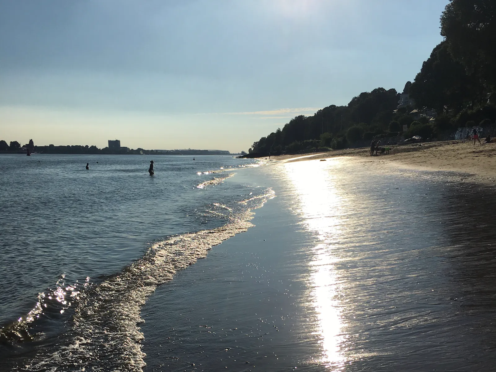 Die Sonne spiegelt sich im ablaufenden Wasser des Elbstrandes