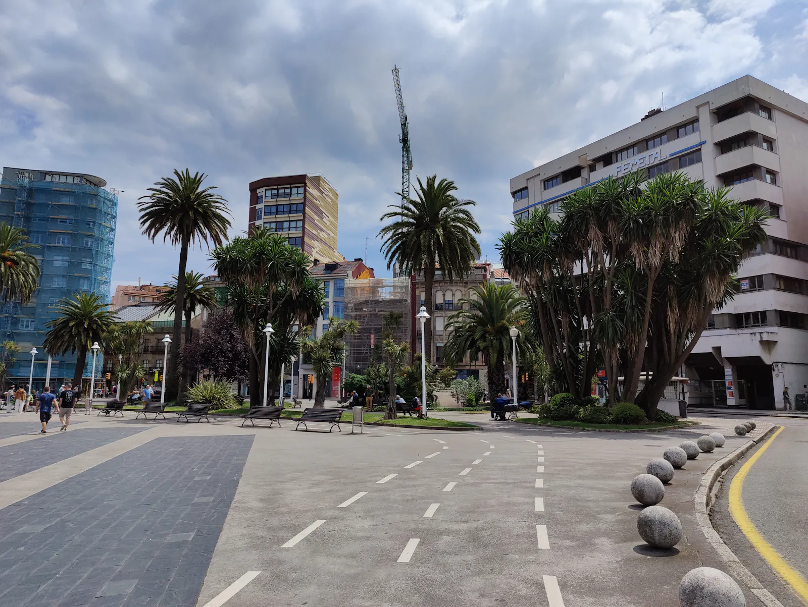 People relaxing among palm trees and modern buildings at the Jardines de la Reina, near Puerto Deportivo de Gijón | Calle Marqués de San Esteban 2, 33206 Gijón, Asturias, Spain