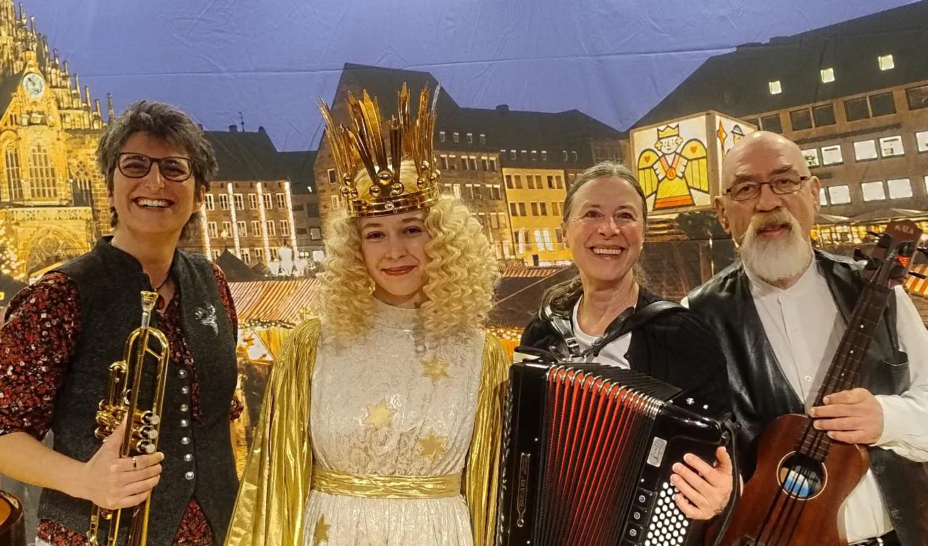 Trompeterin, Akkordeonistin und Bassist rahmen das Christkind ein - vor dem Hintergrund des Nürnberger Marktplatzes