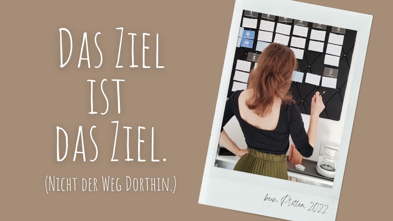Das Foto zeigt die Autorin vor ihrer Pinnwand beim Überarbeiten eines Buch-Plots. Links daneben steht auf hellbraunem Grund: "Das Ziel ist das Ziel. (Nicht der Weg dorthin.)"