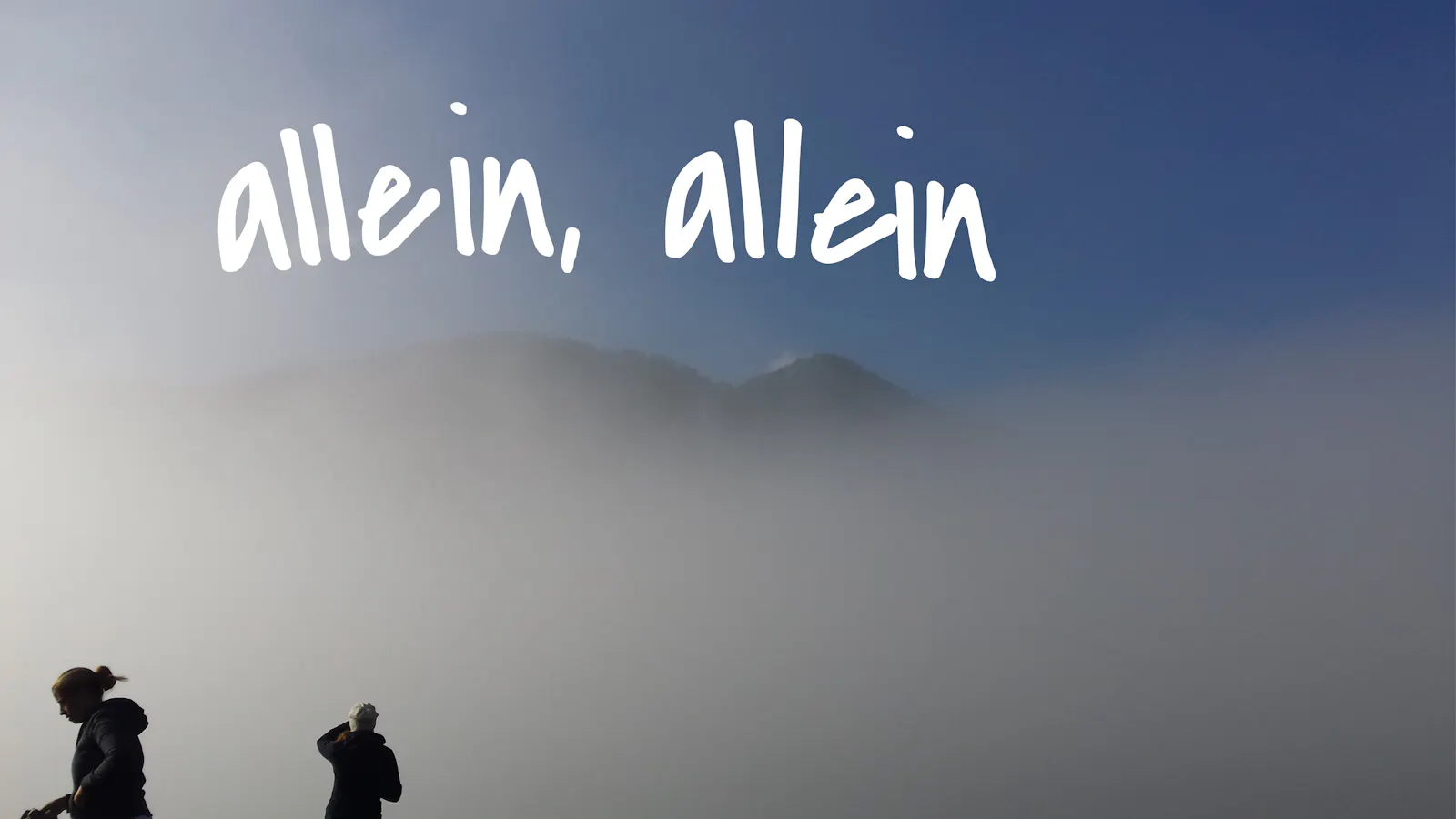 Ein Mann und eine Frau vor einem Berg, der im Nebel kaum zu sehen ist