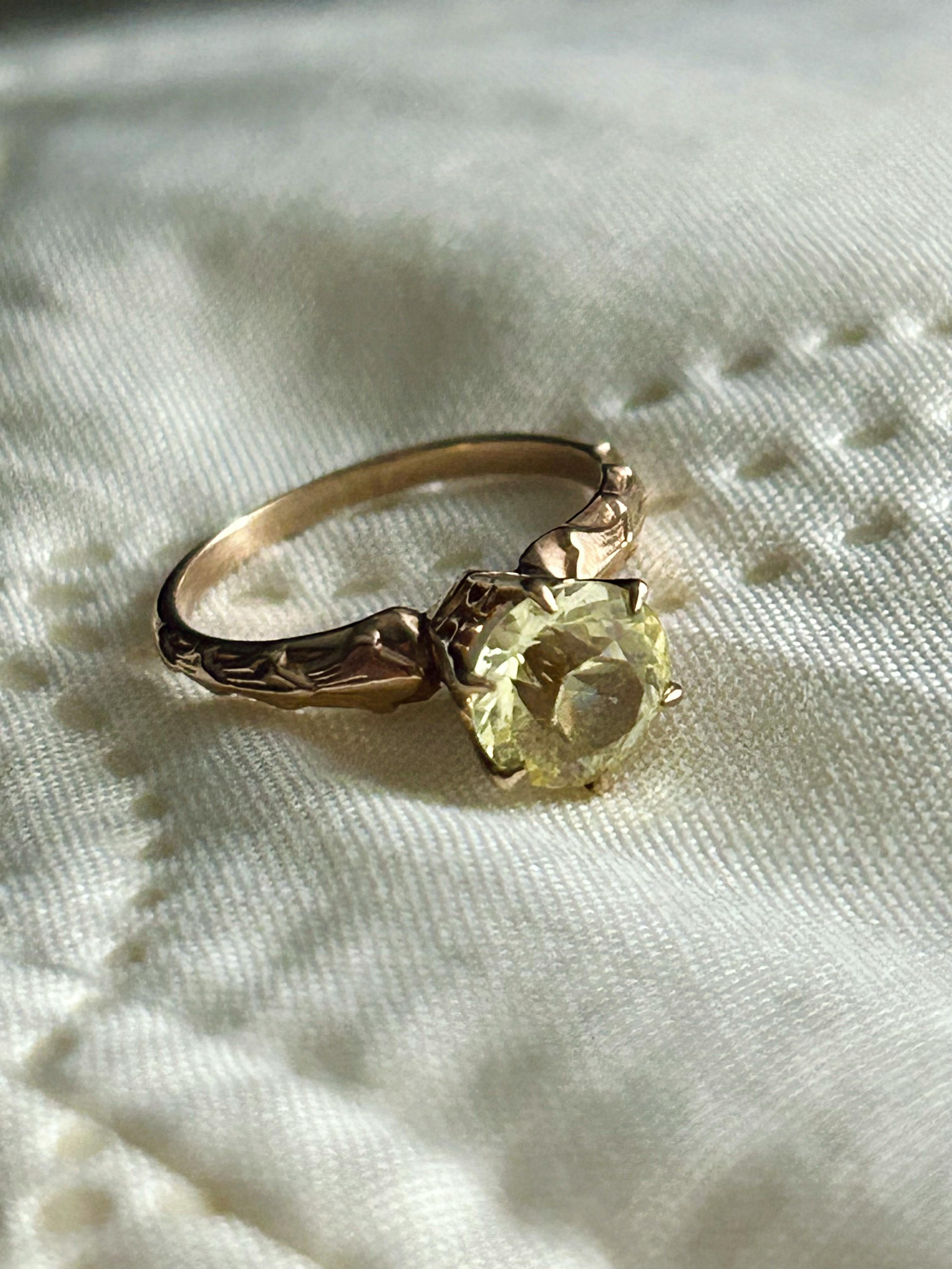 An antique topaz engagement ring with a gold band atop a white sheet.