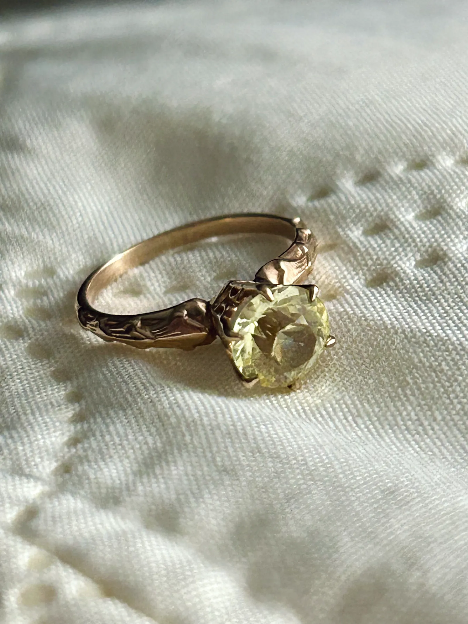 An antique topaz engagement ring with a gold band atop a white sheet.