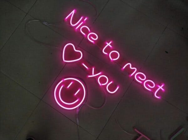 pinker Neon-Schriftzug: nice to meet you mit einem Herz und einem lachenden Smiley