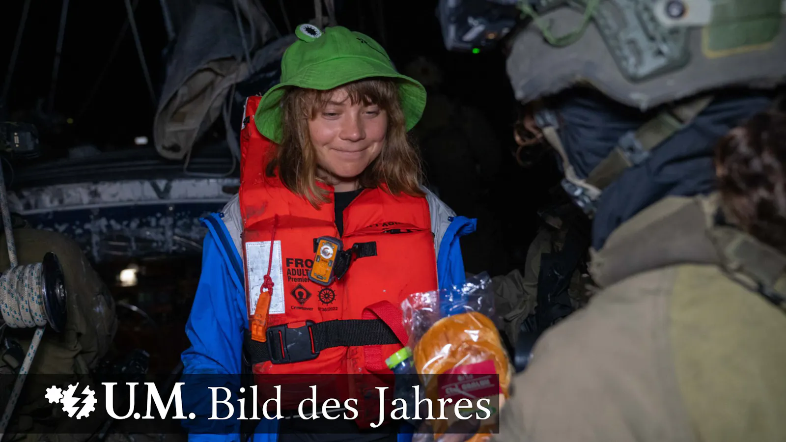 Das bekannt gewordene Foto, auf dem Greta Thunberg lächelnd ein Sandwich von den IDF bekommt. Mit der Bildbeschriftung "U.M. Bild des Jahres".
