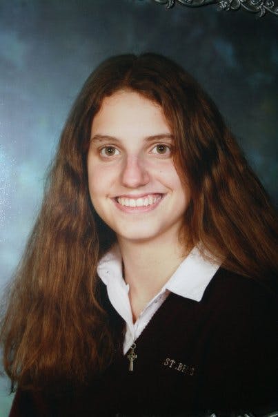 My sister Hannah in the last photo ever taken of her to my knowledge. She is wearing our high school uniform (black sweater over a white dress shirt) and smiling for school picture day against a blue backdrop.