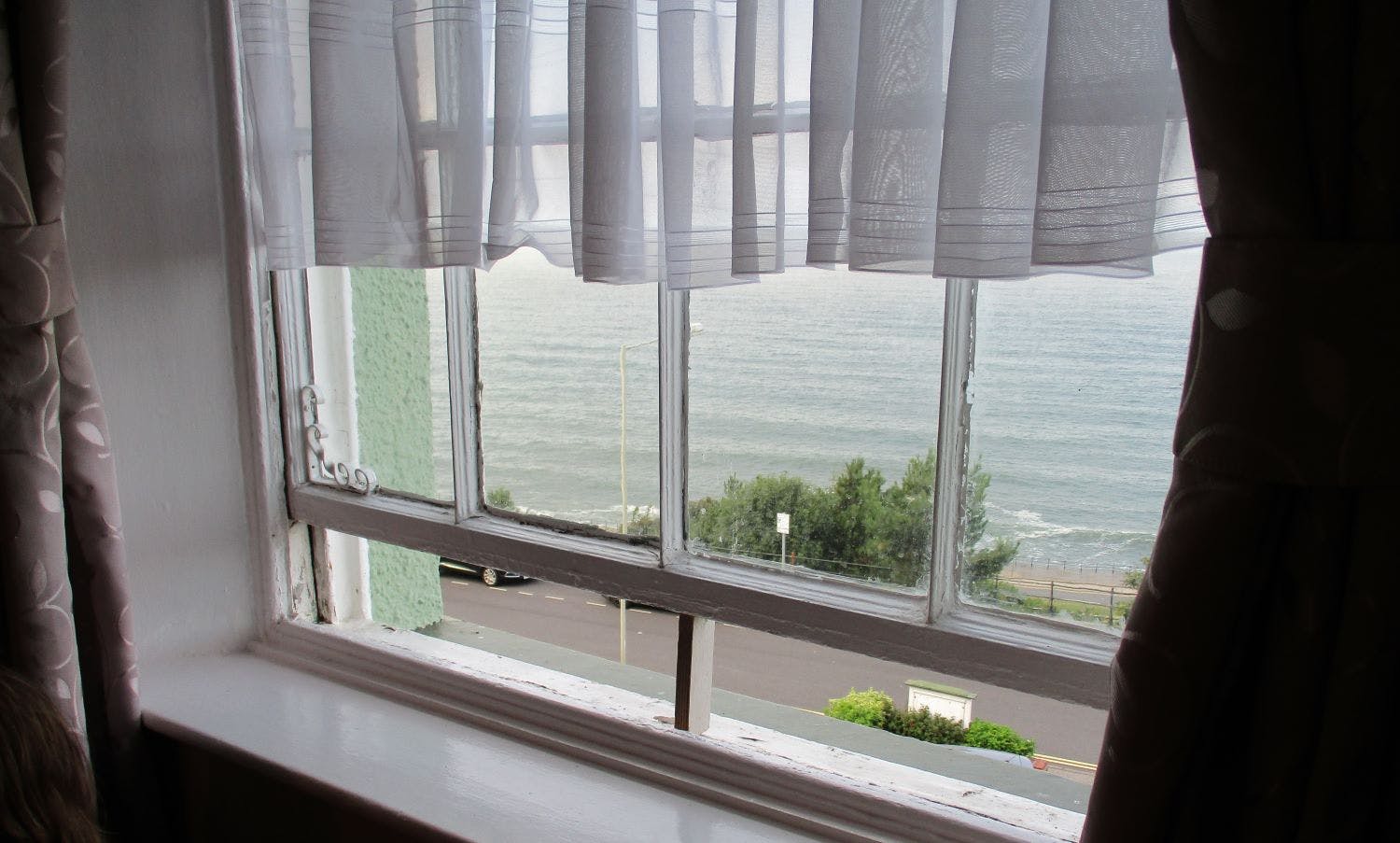 Blick aus einem leicht geöffnete Fenster aufs Meer.