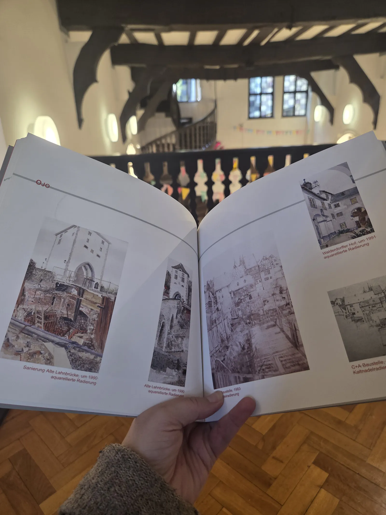 Mit einem Blick ins Buch voll mit Kunstwerken sitze ich in der Kunstsammlung Limburg