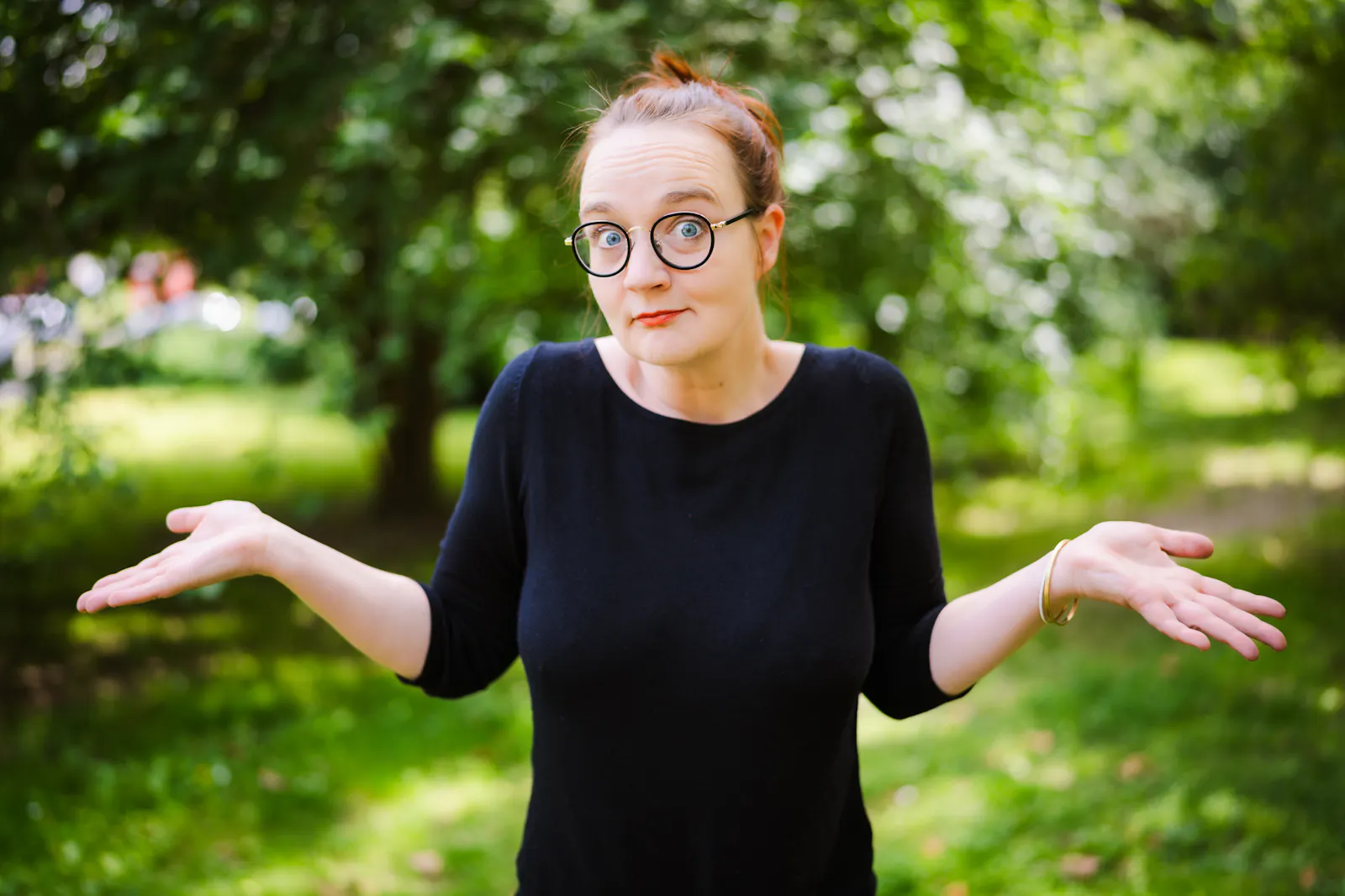 Insa van den Berg, Frau mit Brille, runzelt die Stirn, hochgezogene Schultern, angewinkelte Arme, offene Handflächen.