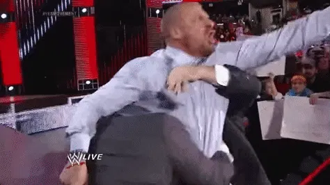 Irgendein WWE-Wrestler wird von Leuten im Anzug aus der Arena geschleift, als Teil der Show