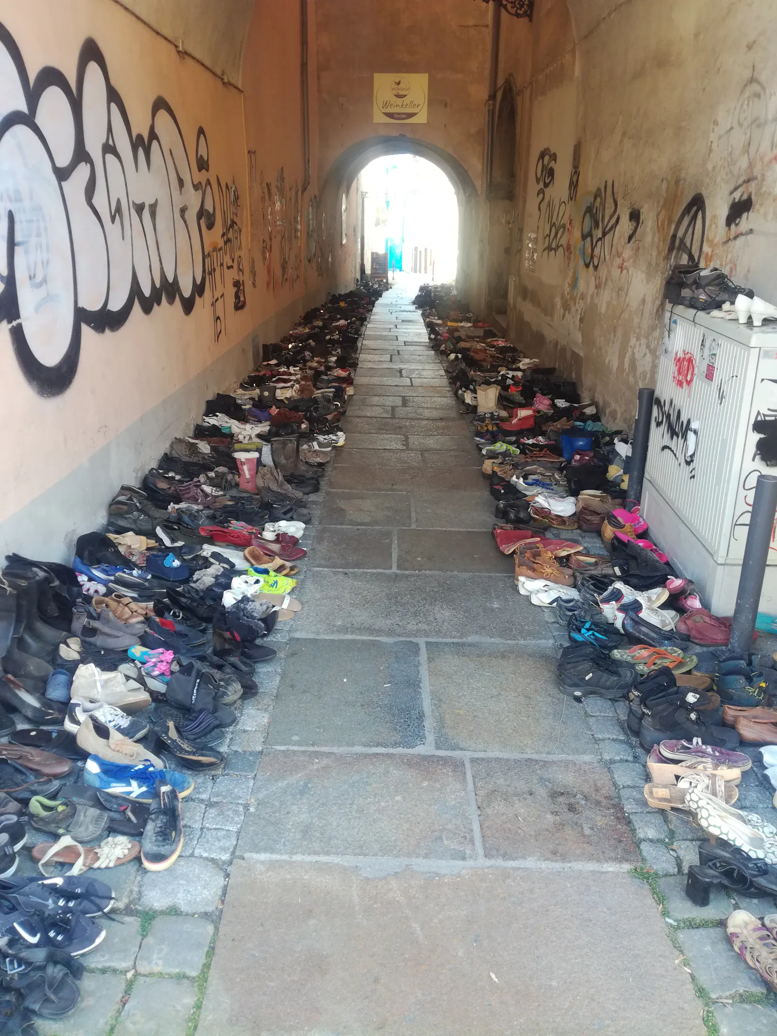 Schuhe in einem Hausdurchgang. Erinnerung an die Toten im Mittelmeer. Zittau, Marktplatz.