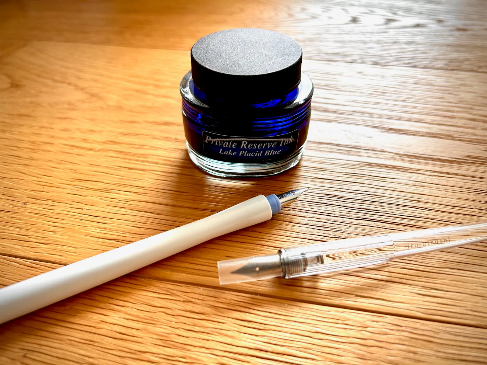 Dip Pens (links von Sailor, rechts von Pilot), außerdem ein Glas uralter Tinte (Lake Placid Blue von Private Reserve, USA).