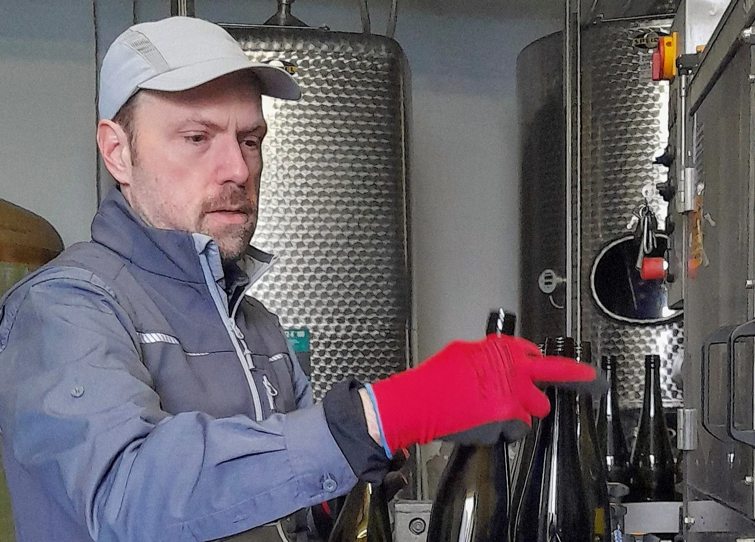 Mann füllt Flaschen mit Wein ab